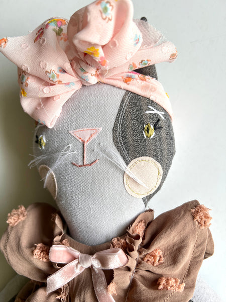 Cat doll with a large bow on a plain background