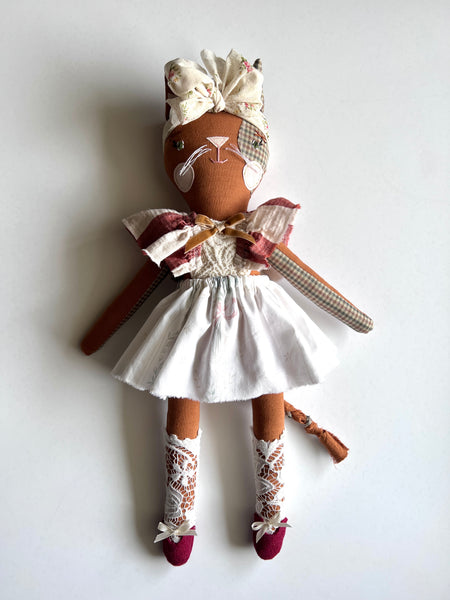Handmade cat doll with a white dress and decorative headband on a light background
