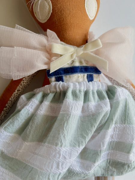 Close-up of a hare doll with a bow and a green textured fabric item.