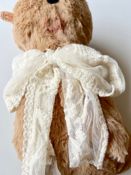 faux fur chick doll with a white lace scarf on a light background