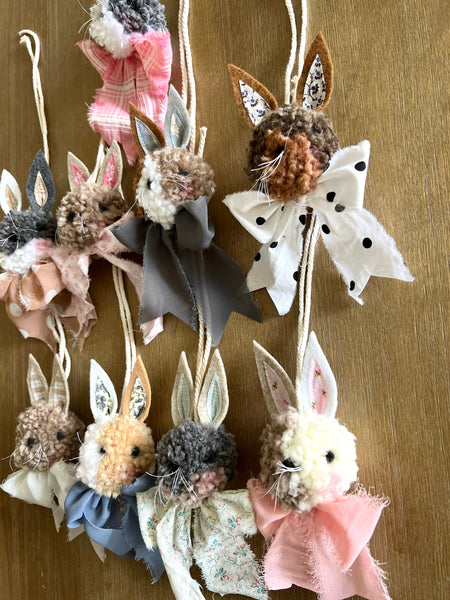 Decorative bunny ornaments with floral and ribbon details on a wooden background