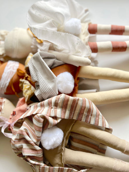 Textile dolls with striped and patterned clothing on a white background