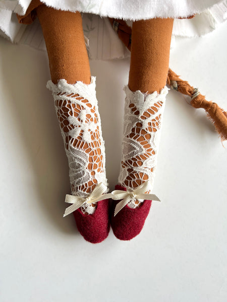 detail of doll legs wearing socks and felt shoes.