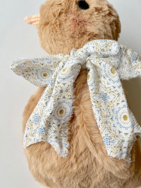 faux fur chick doll with scarf on a light background