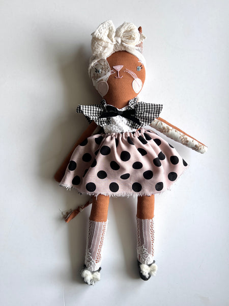 Handmade cat doll with a polka dot dress and white headband on a light background