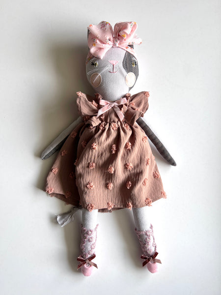 Cat doll in a brown dress with pink flowers on a white background