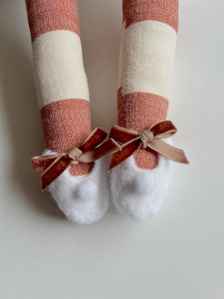Red and white striped socks with a brown bow on a light background
