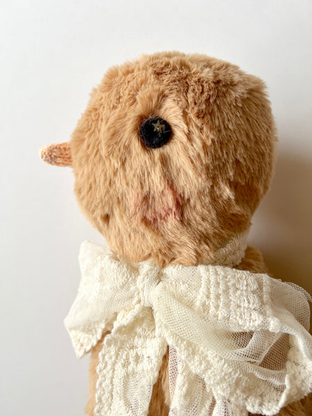 faux fur chick doll with a white lace scarf on a light background