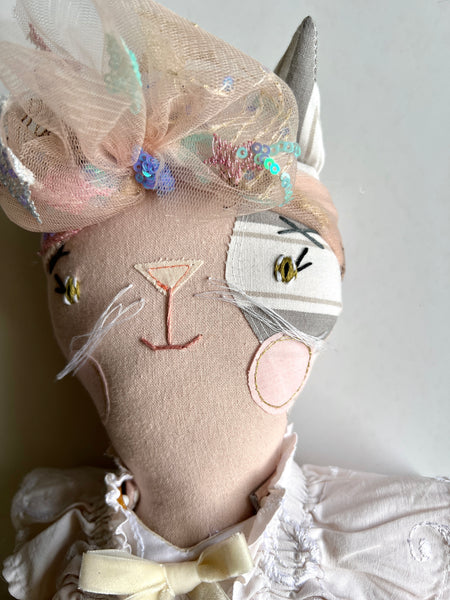 cat with decorative headpiece and white outfit on a plain background