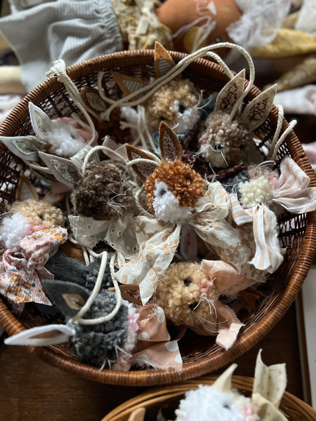 Basket filled with small decorative rabbit poms on a wooden table