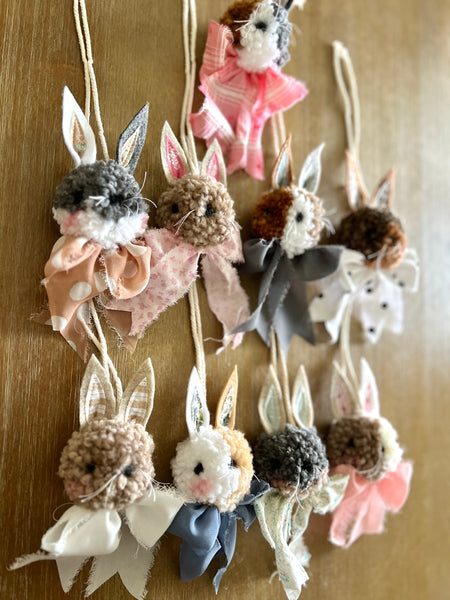 Decorative string of small plush bunny poms with various colors and textures on a wooden background.
