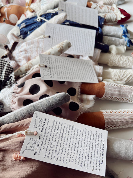 Cat dolls with tags on, showing various fabric textures and colors.