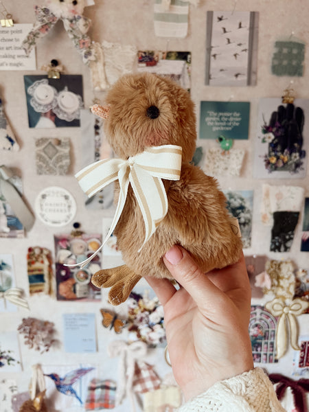 faux fur chick doll with scarf being held up in front of a mood board