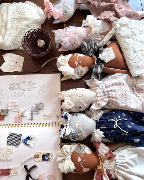 Collection of bespoke cat dolls including clothes and accessories on a wooden surface.