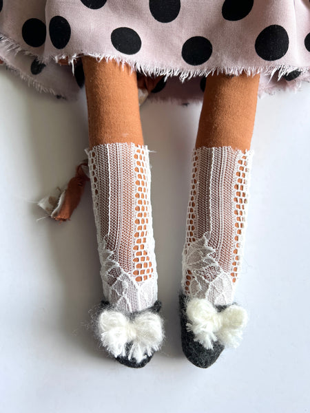 White fishnet socks with pom-poms worn by cat doll.