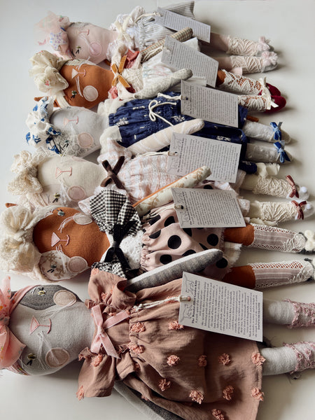 Collection of cat dolls with hang tags on a white surface