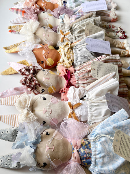 Collection of handmade fabric animals and accessories on a white surface
